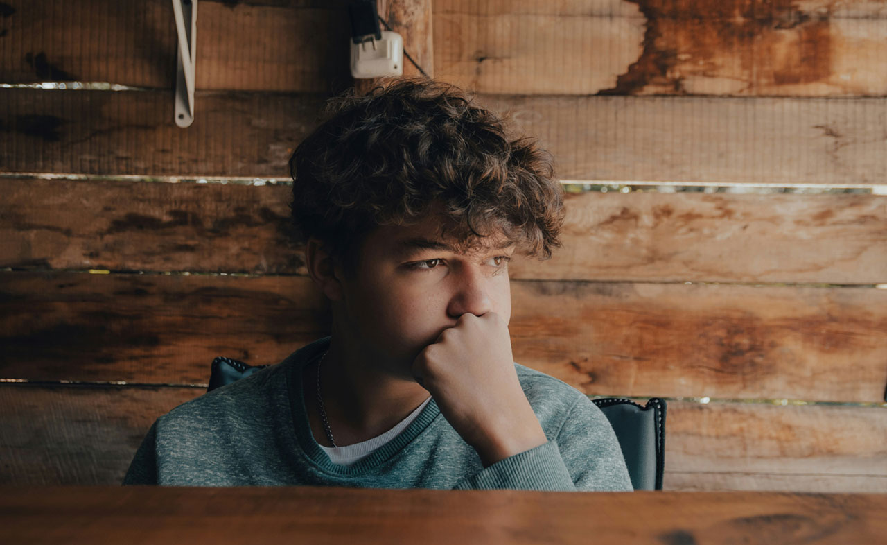 Photo of a boy sitting at a table thinking