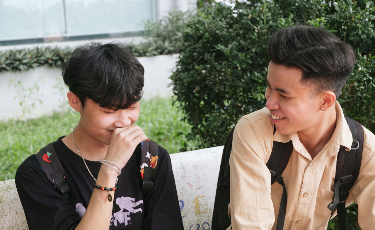 A photo of two students laughing outside of school.