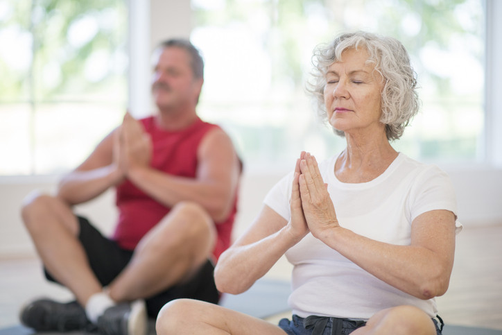 A mature man and woman practicing yoga. 