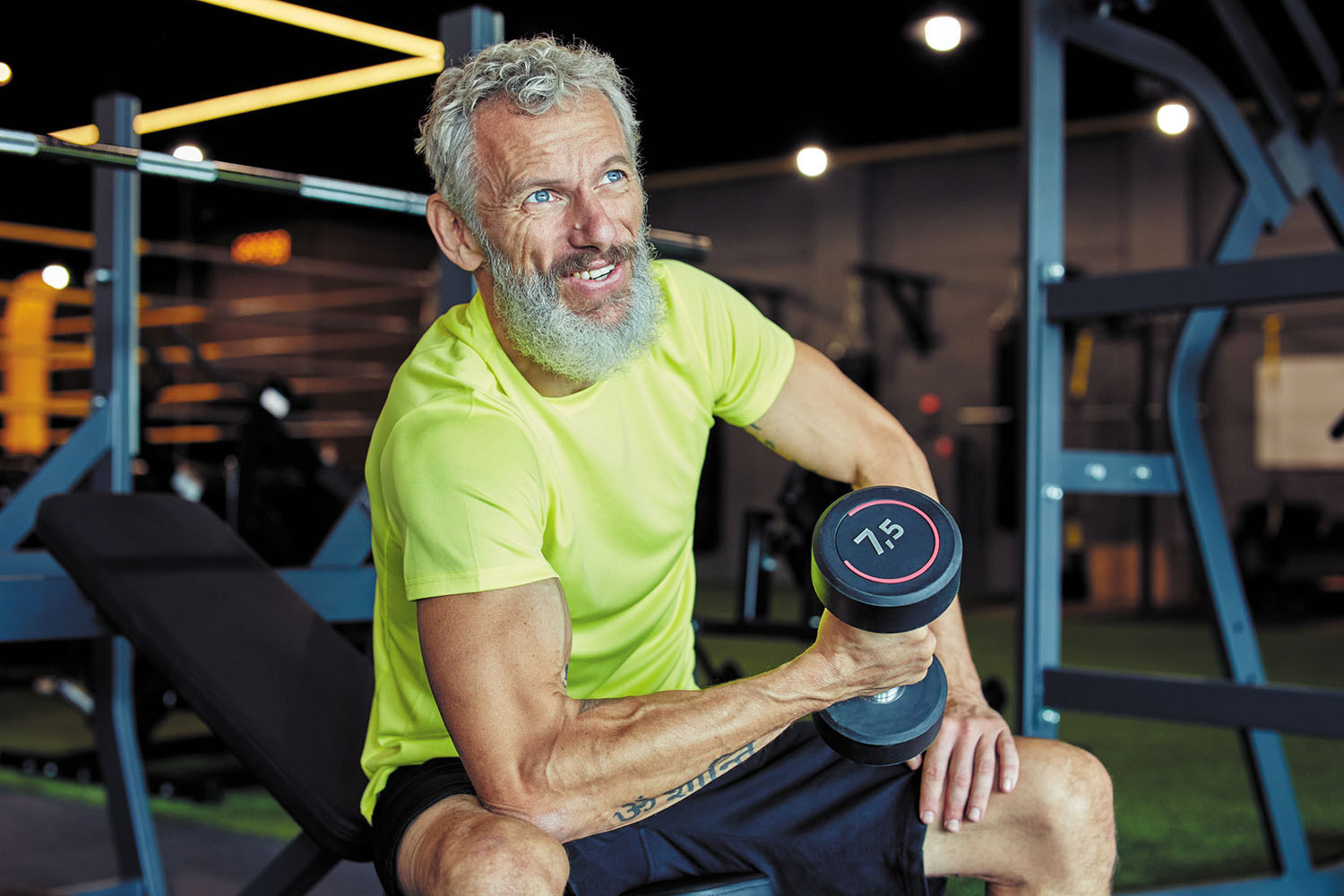 photo of a mature man doing a bicep curl in a gym