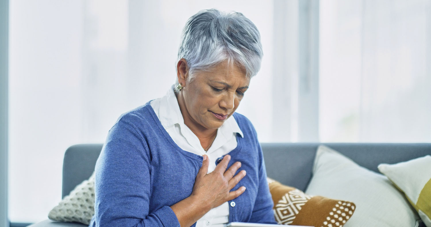 photo of an older woman holding her hand over her heart as if experieicing pain