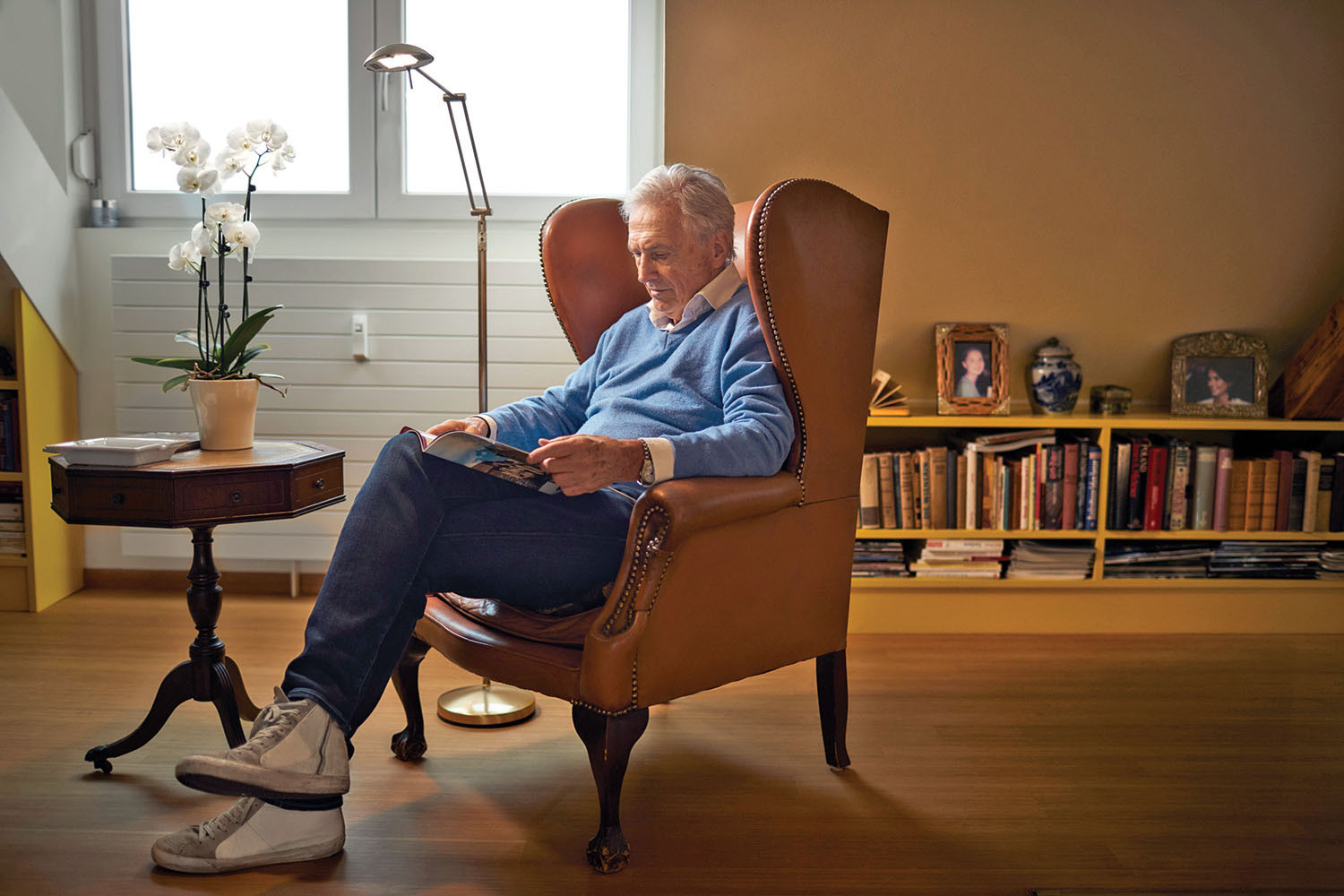 photo d'un homme assis sur une chaise dans son salon en train de lire un livre