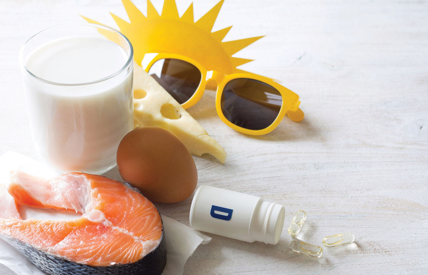 photo représentant les moyens d'augmenter l'apport en vitamine D : alimentation (verre de lait, fromage, œuf, saumon) ;  exposition au soleil (lunettes de soleil);  bouteille de suppléments