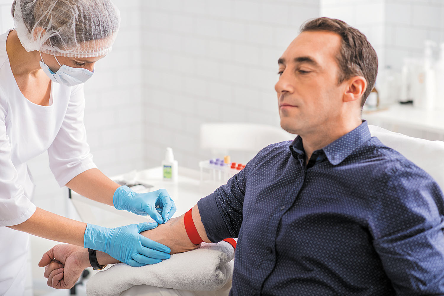 photo d'un homme essayant de se détendre tout en se faisant prélever du sang pour un test de laboratoire