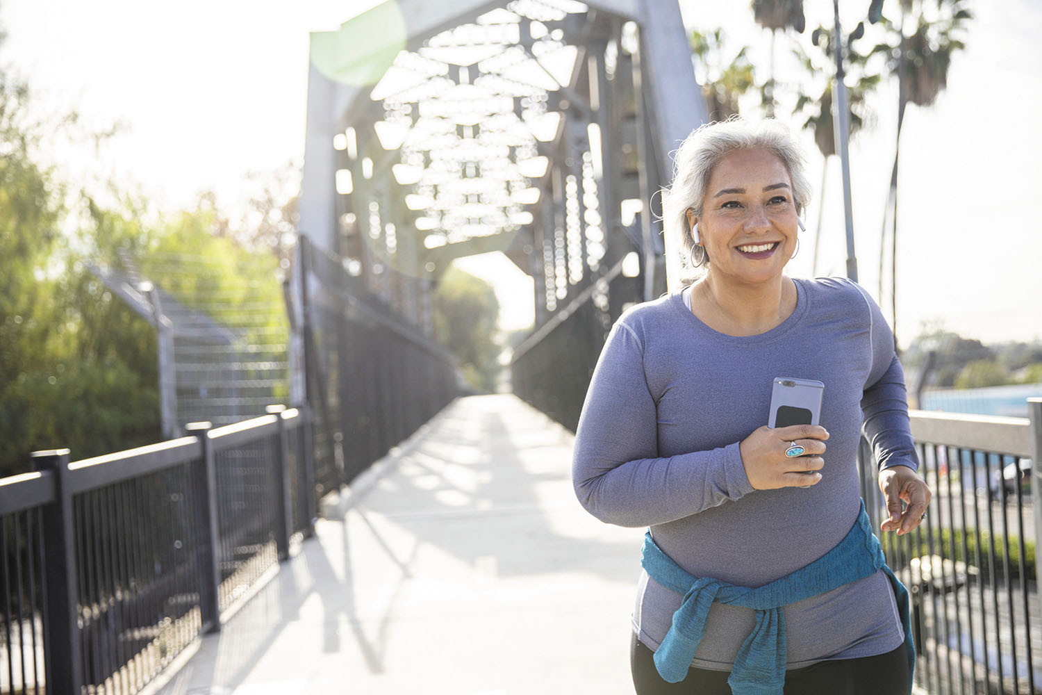 photo d'une femme souriante en faisant du jogging sur une passerelle piétonne