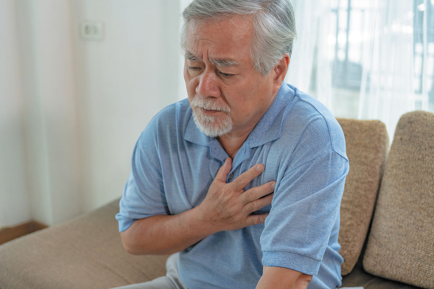 photo of a mature man experiencing chest pain, holding his hand to his chest