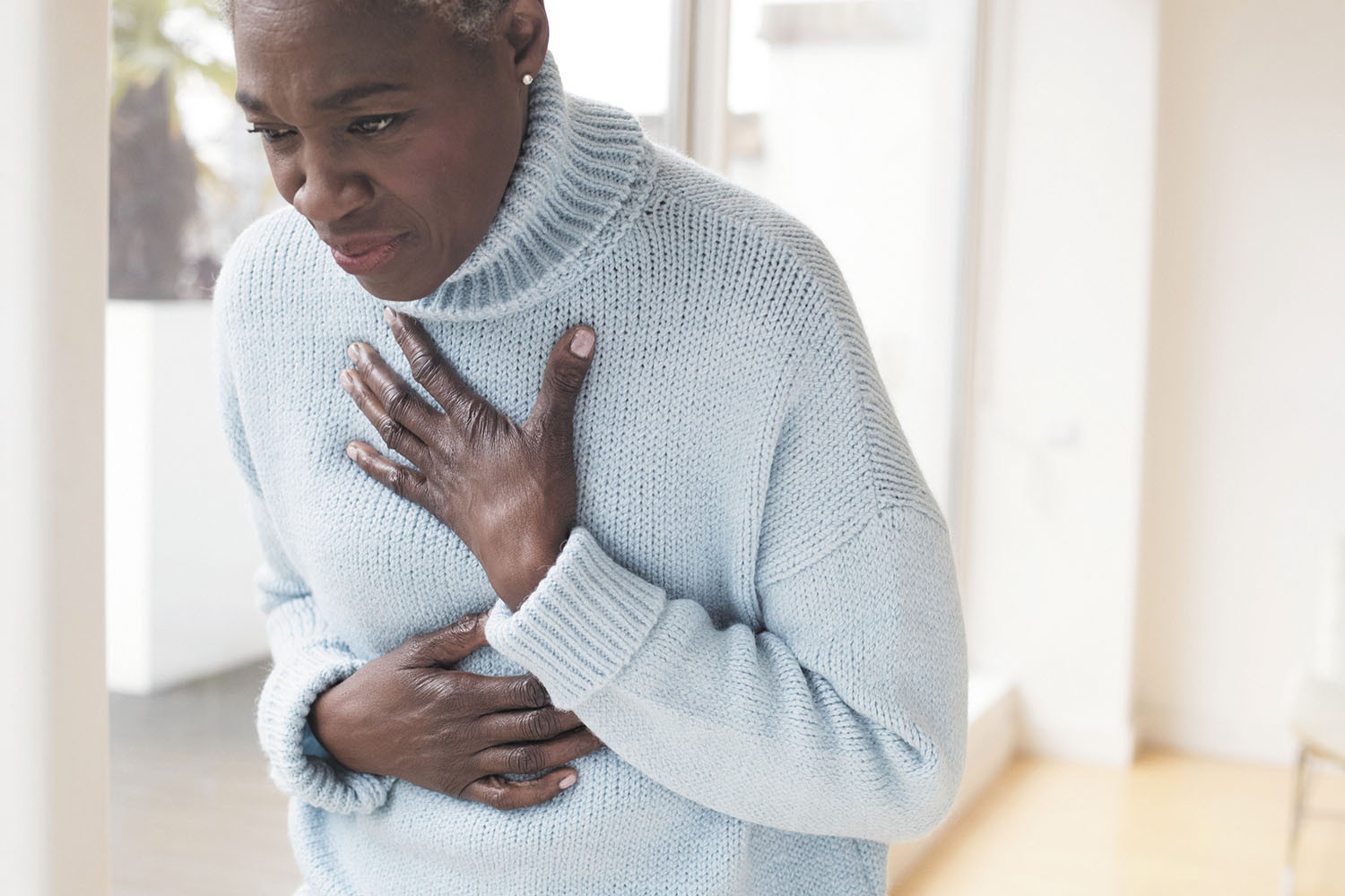 photo d'une femme tenant une main sur le haut de sa poitrine et l'autre sur son ventre, souffrant d'un inconfort dû au reflux gastro-œsophagien