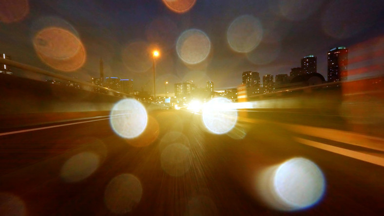 Résumé de la circulation sur l'autoroute de la ville la nuit avec des phares éblouissants formant de gros points colorés 