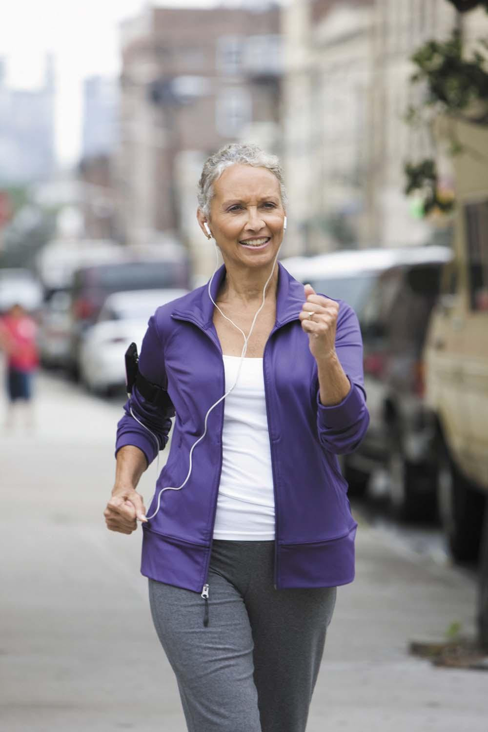 A woman walks briskly on a city street.