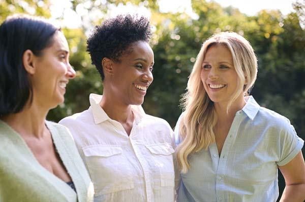 Three smiling middle-age women spending time outdoors.