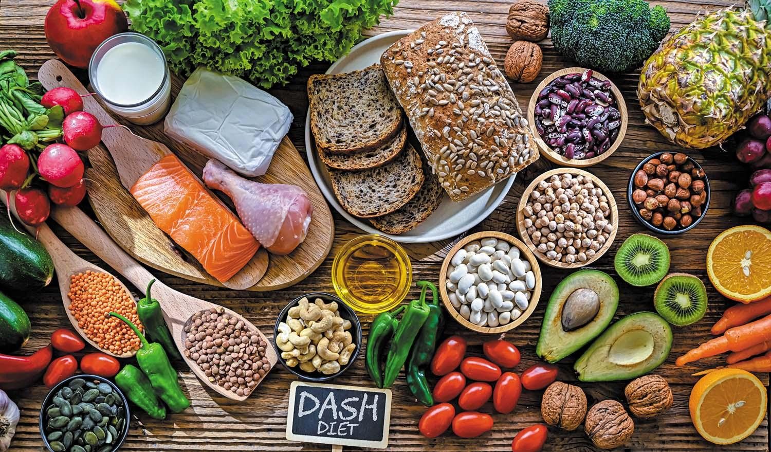 Artfully arranged assortment of foods eaten in the DASH diet, including fish, nuts, whole grains, fruits and vegetables, and more.