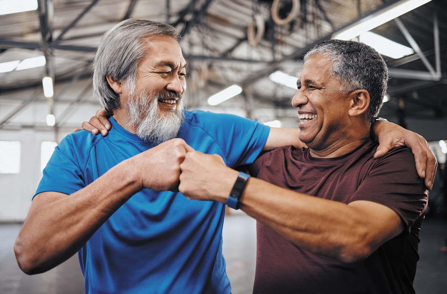 Two men in a gym fist-bump each other after a successful workout.