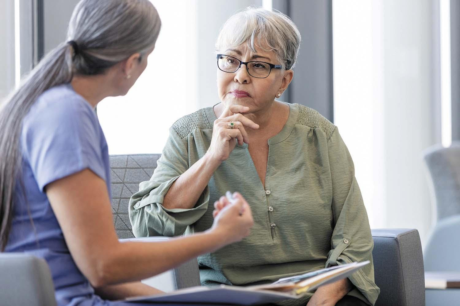 A doctor explains menopause symptom relief options to a patient in the doctor's office.