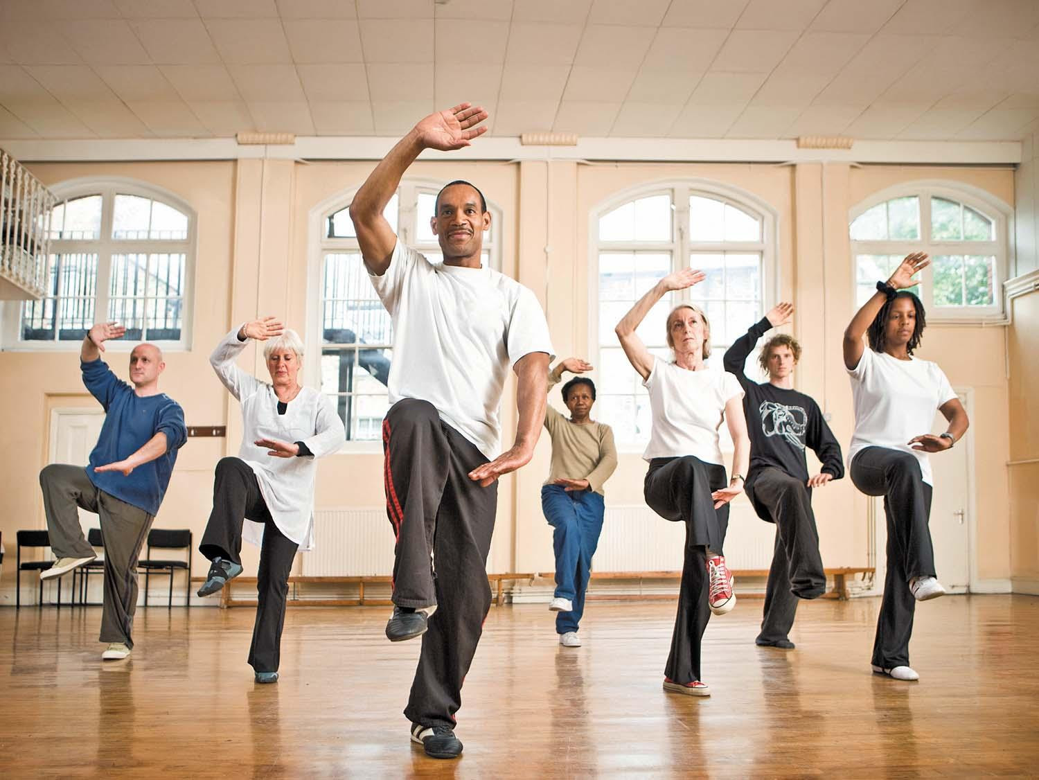A group of people doing tai chi movements during a group class.