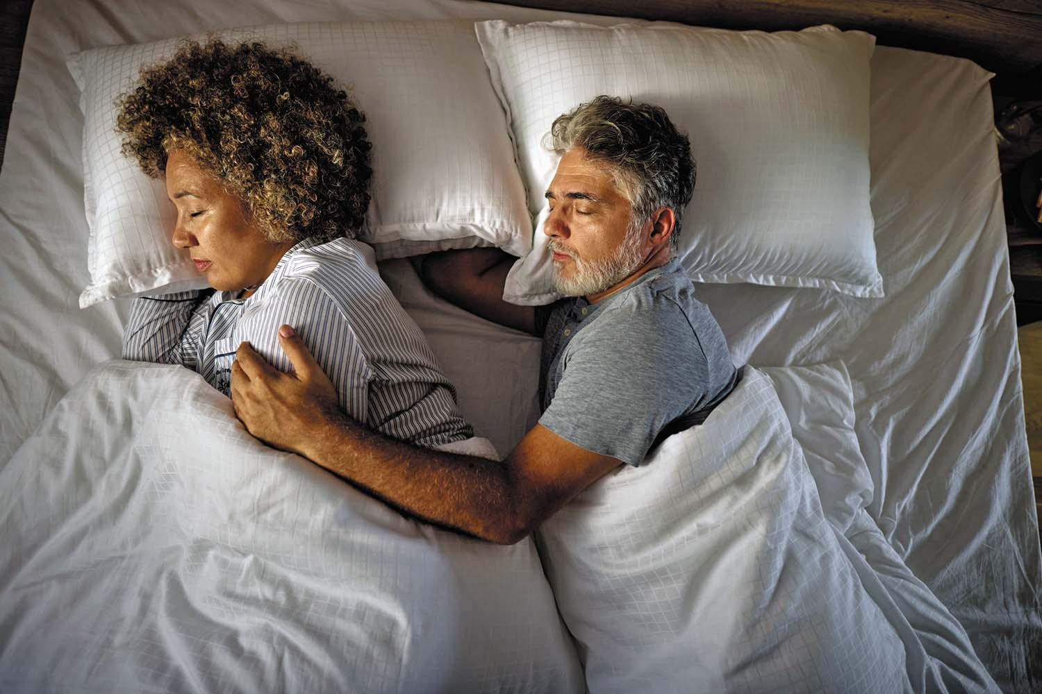View from above of a couple asleep in bed.