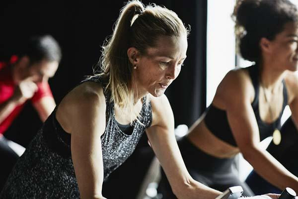 A woman is intently focused during an indoor cycling class in fitness studio.