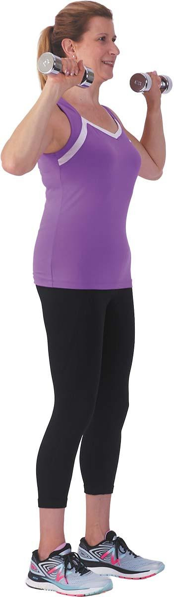 A woman performs the first step of the overhead press exercise (holding weights at shoulder height).