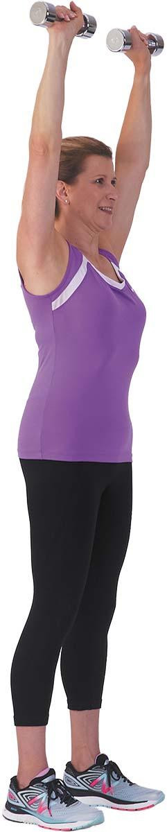 A woman performs the second part of the overhead press exercise (lifting the weights over the head).