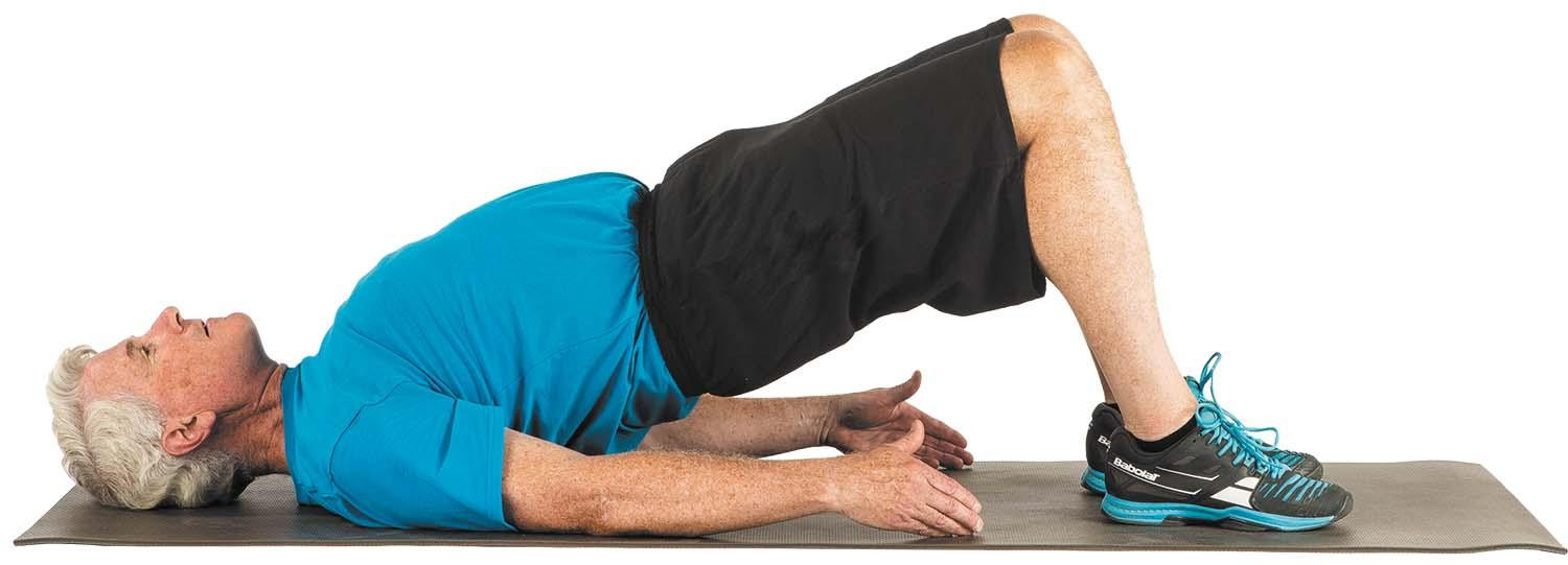A man performs the bridge exercise as described in the article.