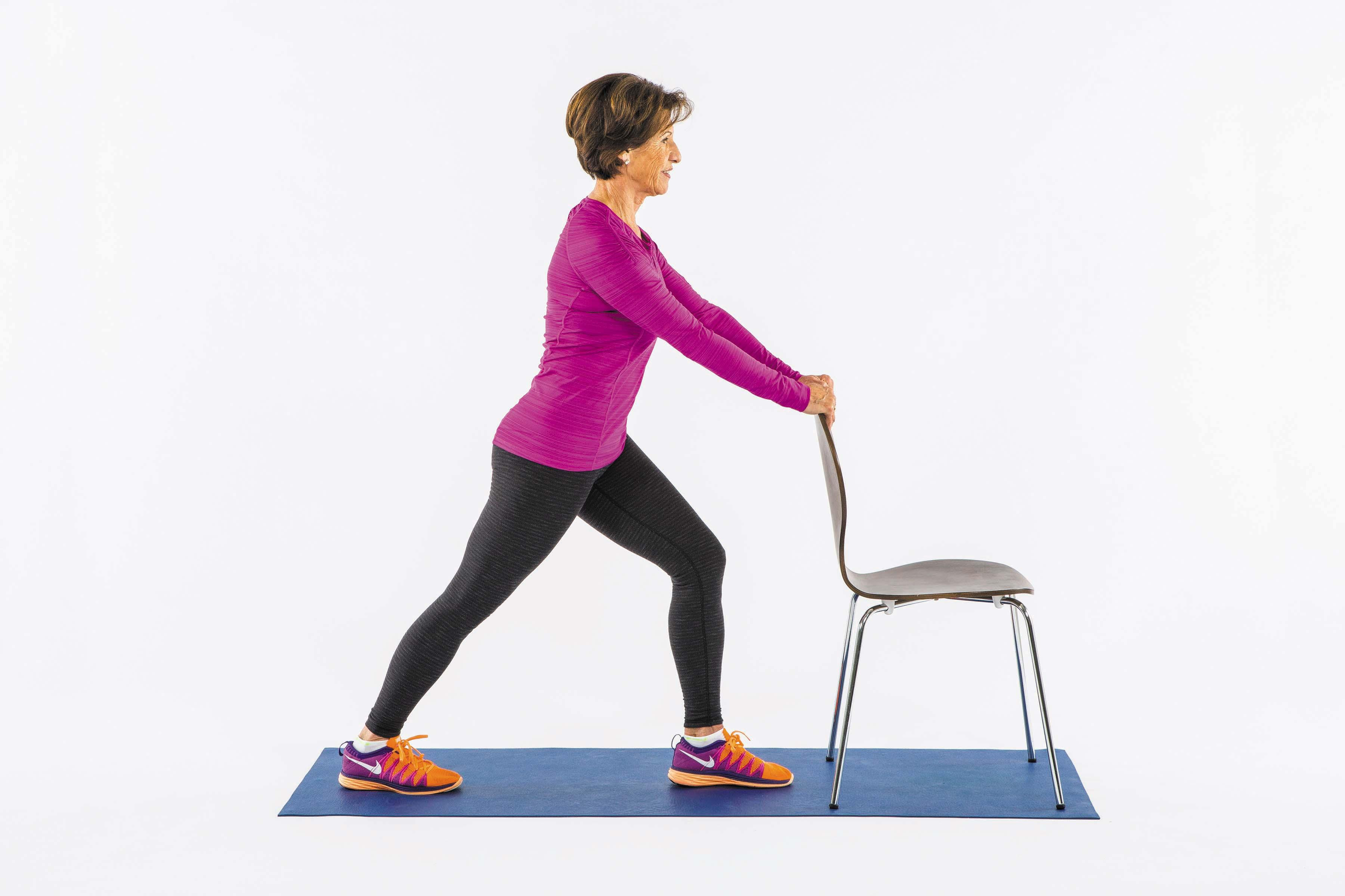 A woman performs the calf stretch exercise as described in the article.