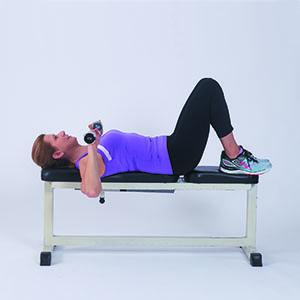 A woman in the starting position for the bench press exercise as described in the article.