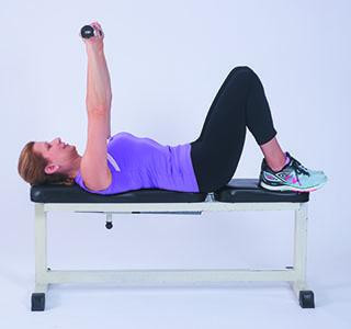 A woman showing the form and movement for the bench press exercise as described in the article.