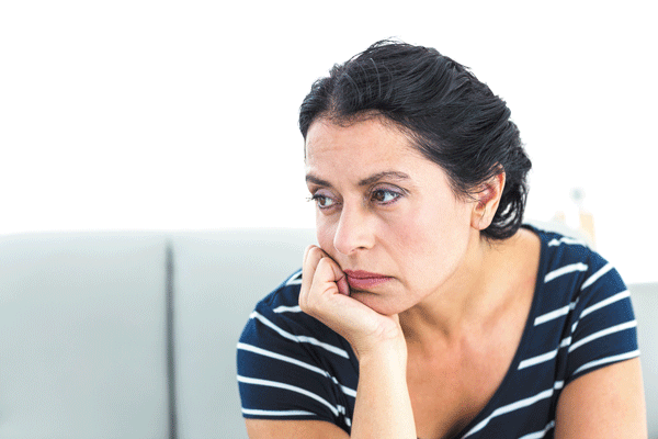 A woman sitting on a couch with her hand on her chin