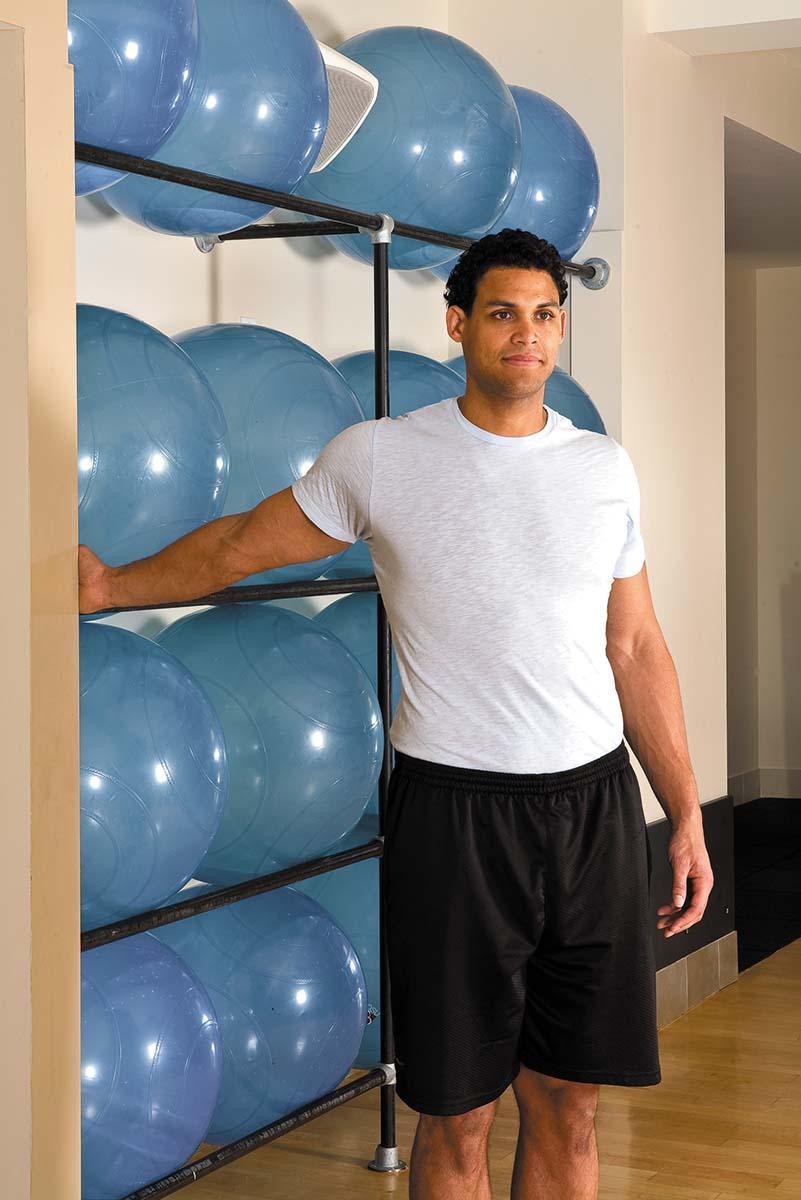 A man shows how to perform the doorframe stretch exercise as described in the article.