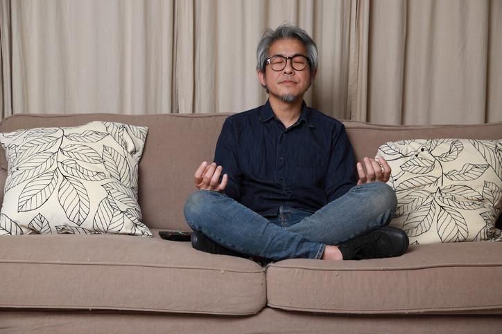 The senior Asian man sitting on the sofa in the living room.