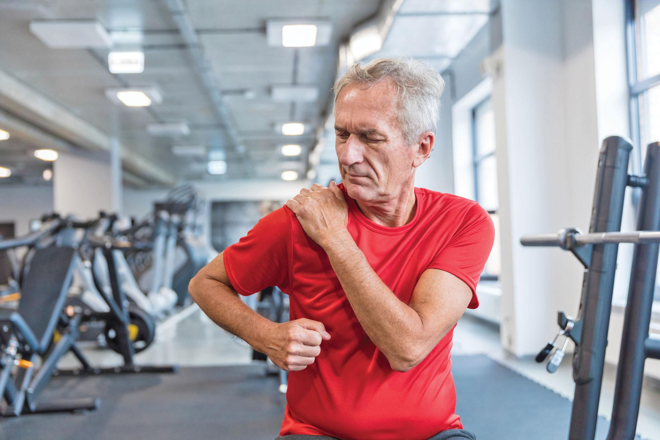 man gripping shoulder in gym