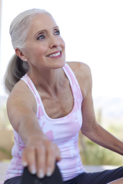 A mature woman stretches as part of an exercise routine.