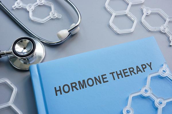 A hardcover book titled hormone therapy on a table alongside plastic models of chemical structures and a stethoscope.