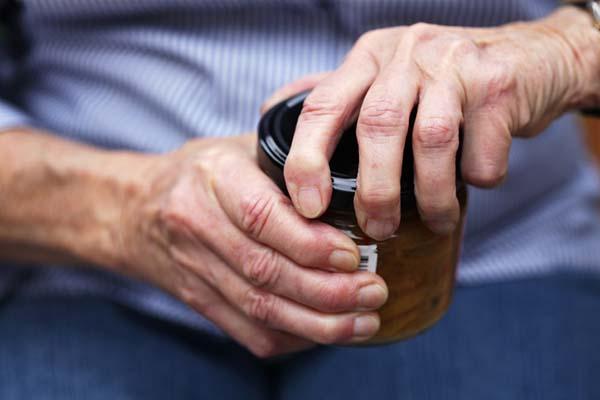 Cropped image showing the hands of a man attempting to open a jar.
