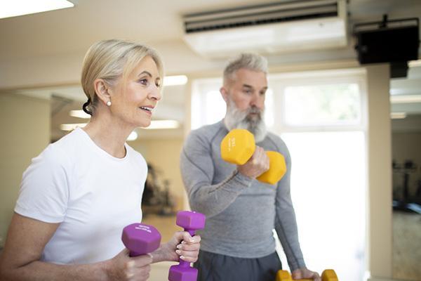 A mature couple exercises together using hand weights.