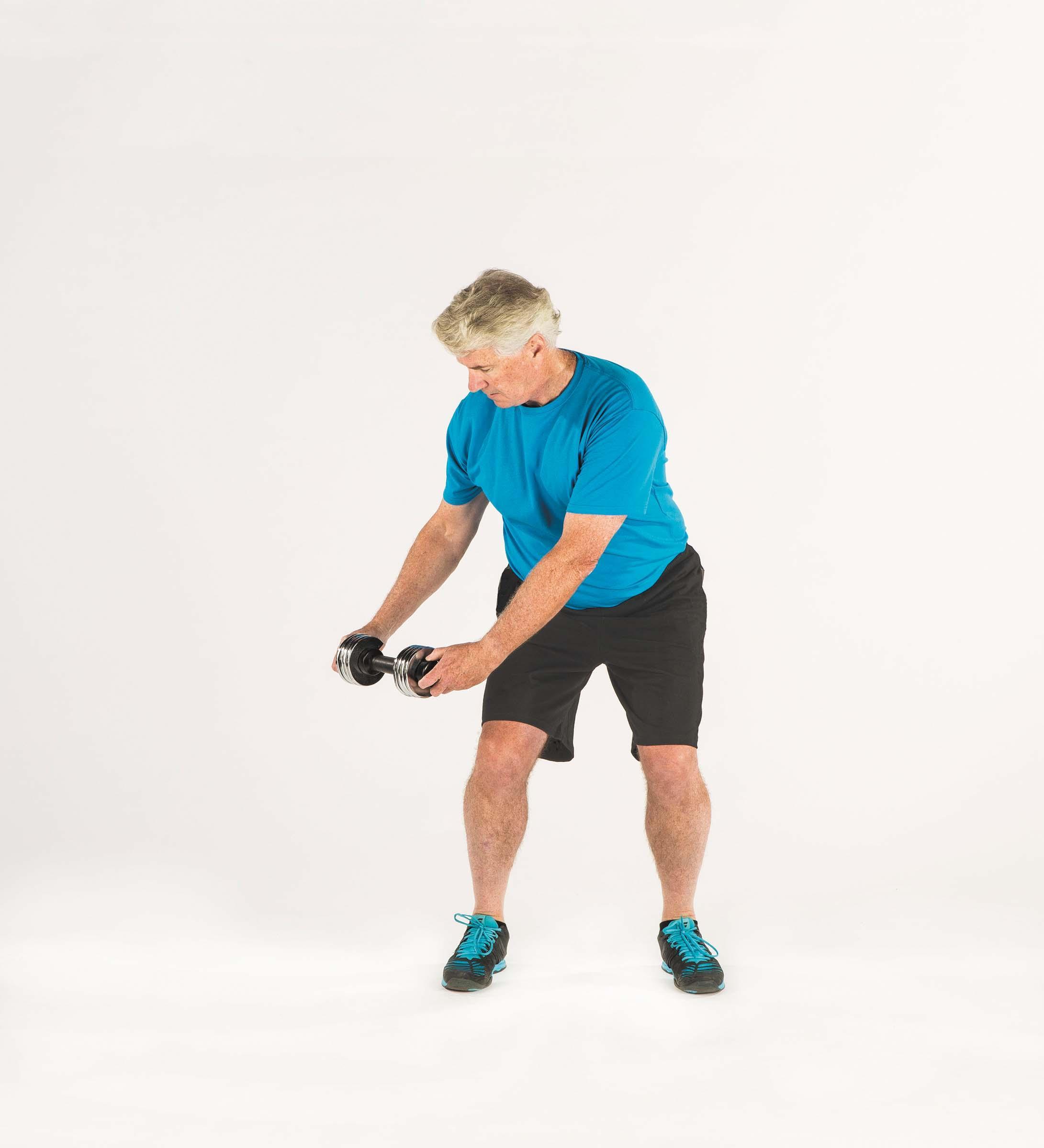 A man shows the starting position for the wood chop exercise as described in the article.