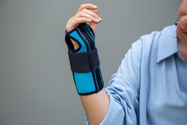 A woman wearing a wrist brace holds up her arm.