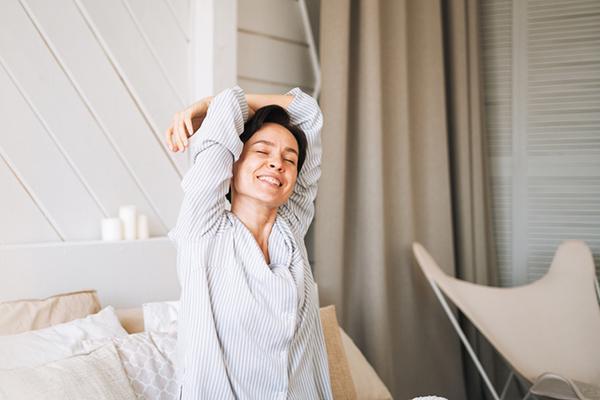 A woman stretches her arms above her head as she wakes up refreshed.