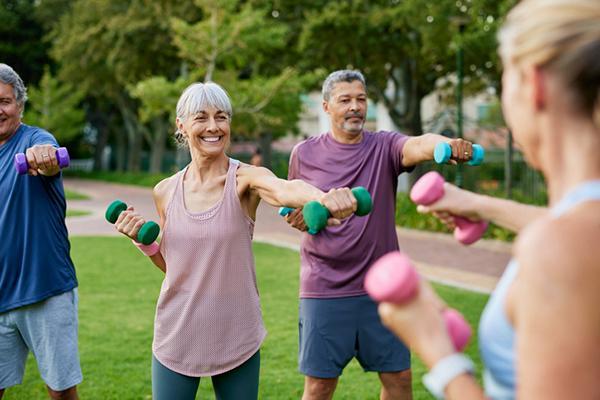 A group of seniors working out with hand weights in a park.