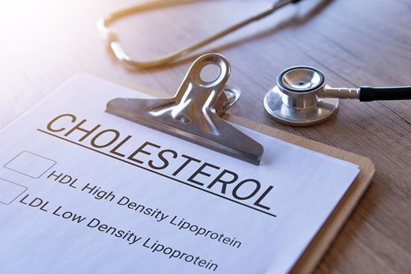 Close-up of a clipboard with a blank cholesterol test form on it, on a desk alongside a stethoscope.