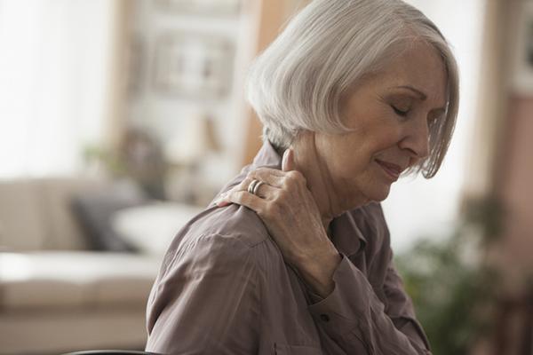 A senior woman experiencing pan rubs her shoulder.