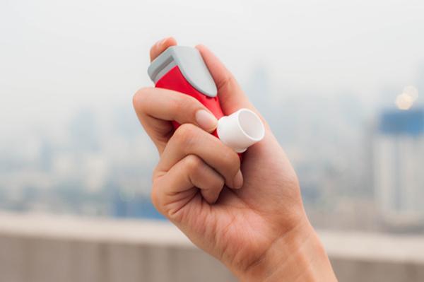 A hand holds an asthma inhaler.