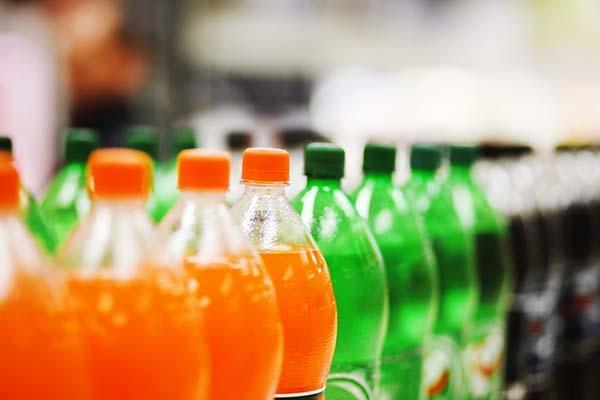 A row of soda bottles (no labels are visible) in assorted flavors with brightly colored caps.