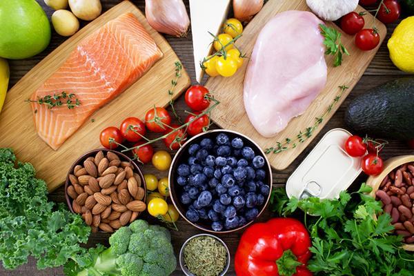 An assortment of foods with anti-inflammatory properties: salmon, chicken, almonds, blueberries, broccoli, peppers, kidney beans, and more.
