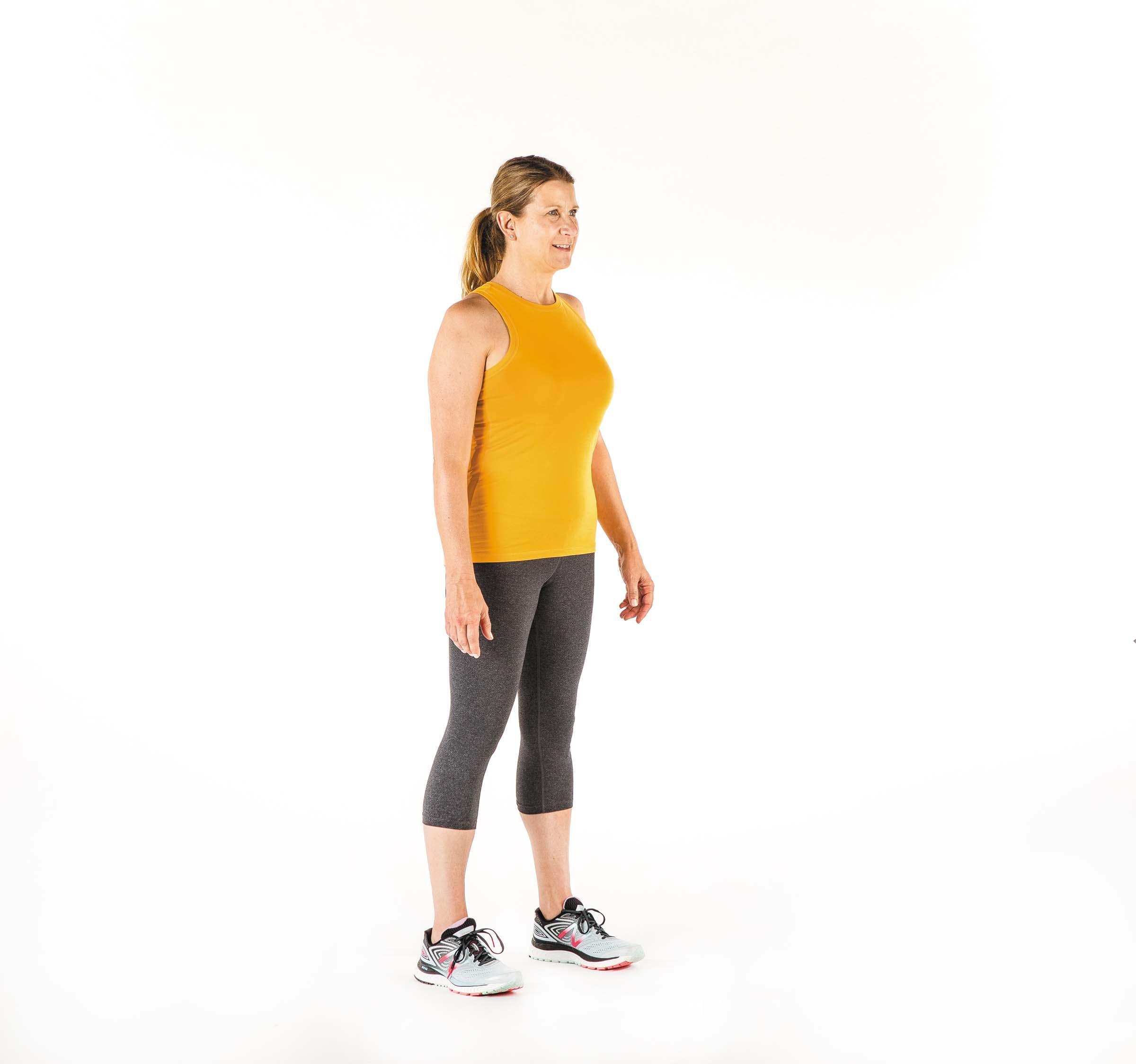 A woman in the starting position for the squat exercise as described in the article.