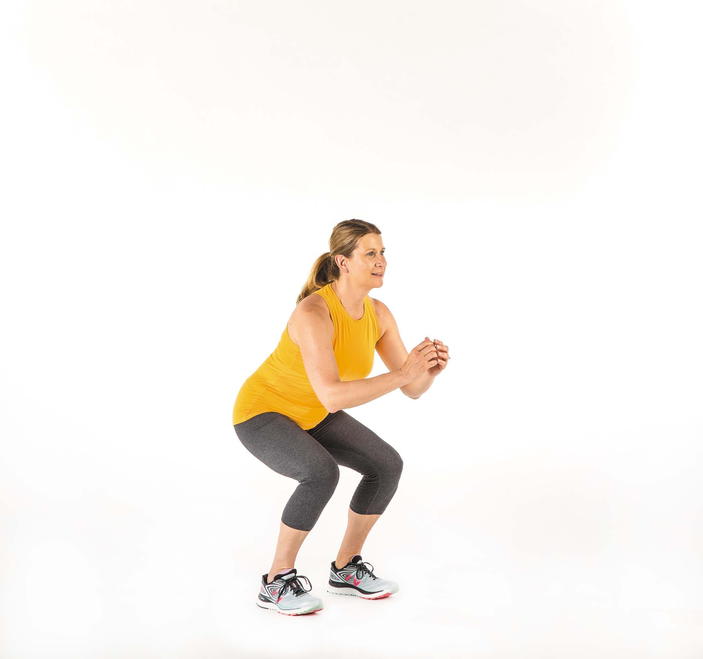 A woman demonstrating the movement for the squat exercise as described in the article.
