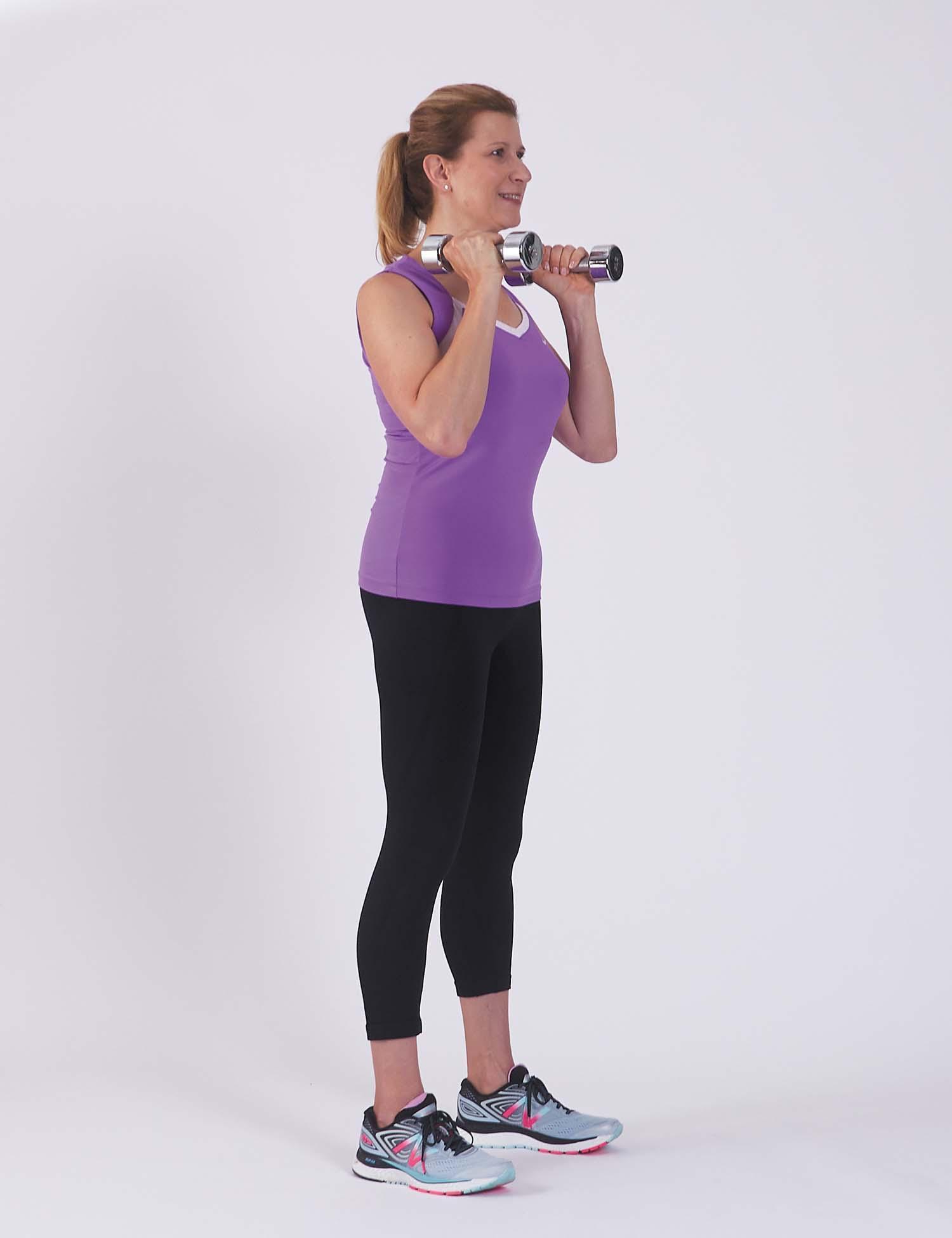 A woman in the starting position for the squat with weights exercise as described in the article.