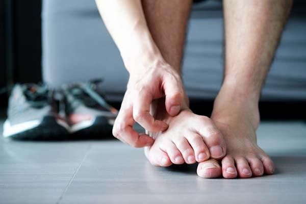 Close-up of a man's hand scratching one of his feet.