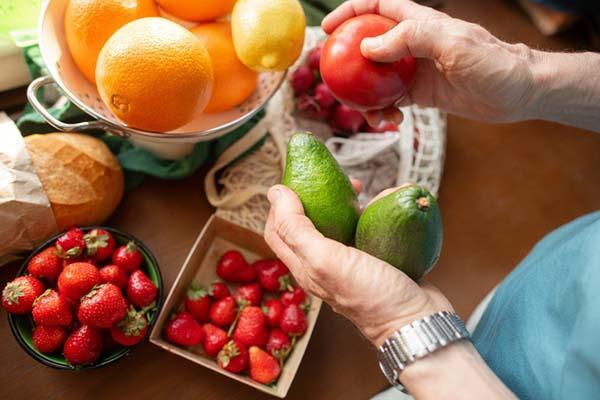 Overhead view of the hands of a man unpacking fruits and vegetables from a reusable grocery bag.