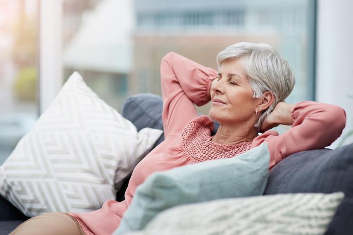 Shot of cheerful mature woman laid back and relaxing on her sofa at home