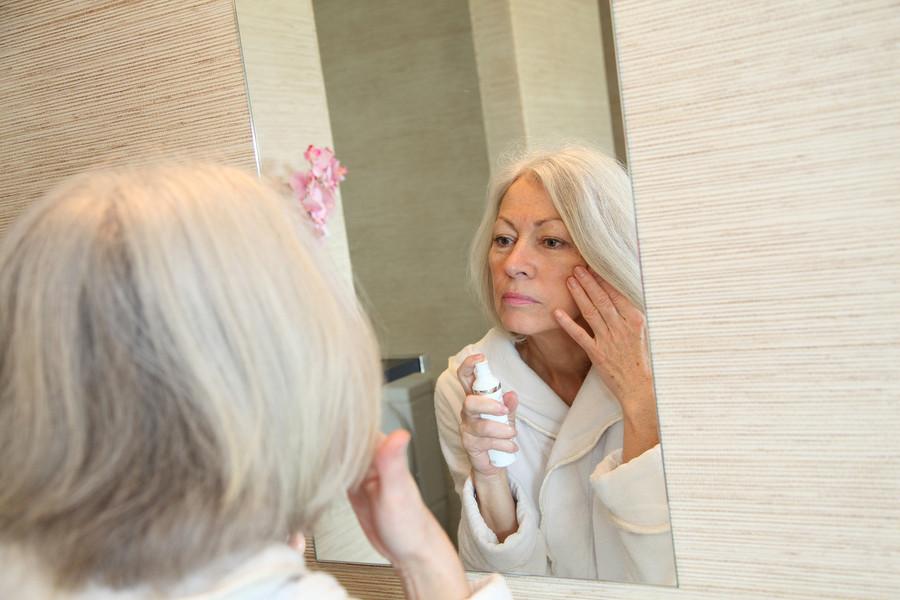 A woman is looking at her reflection in the mirror